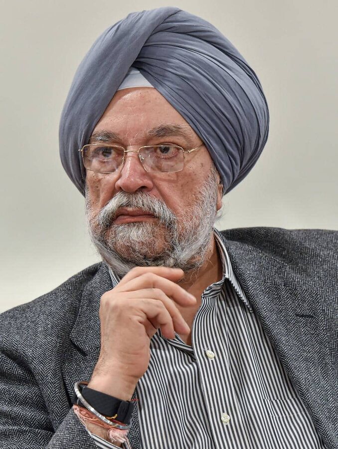 Hardeep Singh Puri in a grey turban and herringbone jacket, resting his chin on his hand