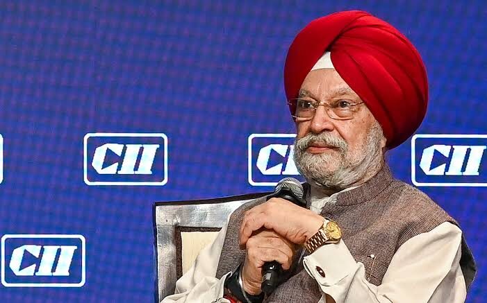 Hardeep Singh Puri in a red turban holding a microphone during a CII session