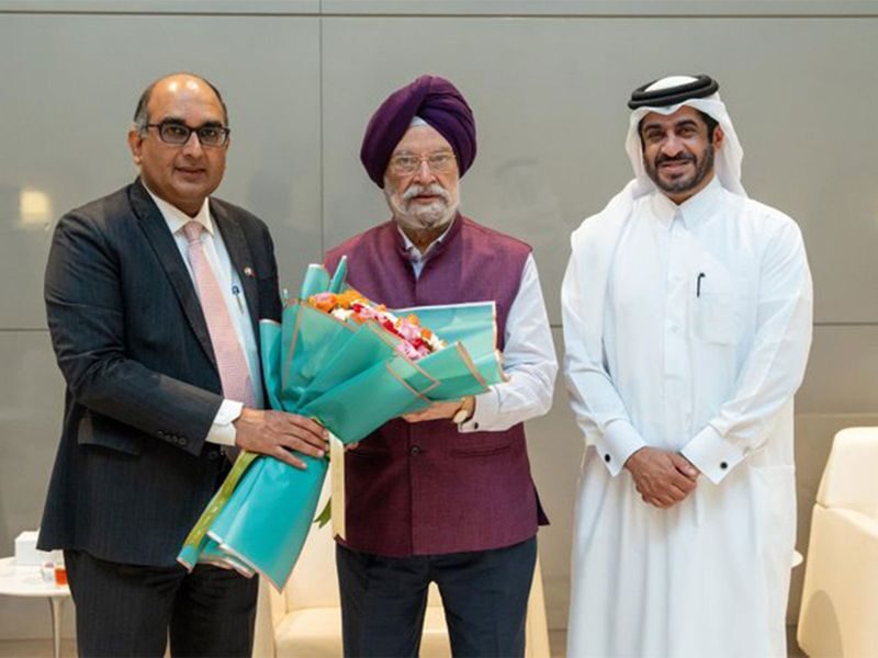 Hardeep Singh Puri holding a bouquet between two officials, one in a suit and one in Gulf attire