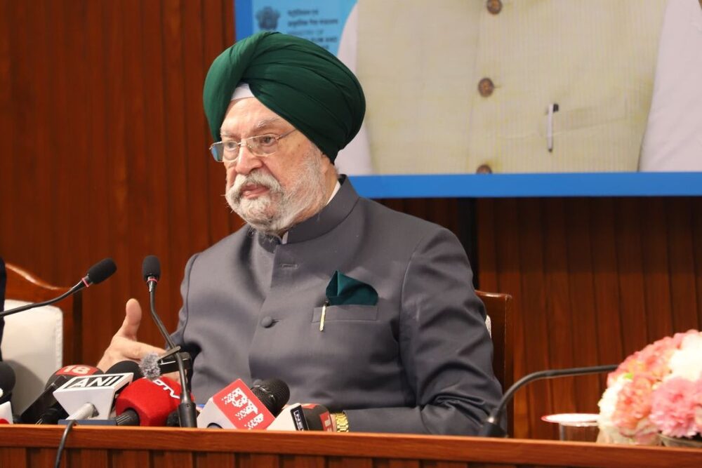 Hardeep Singh Puri in a green turban and grey bandhgala at a press briefing with news-agency microphones