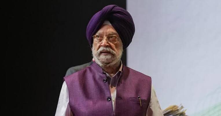 Hardeep Singh Puri in a purple turban and waistcoat walking on stage