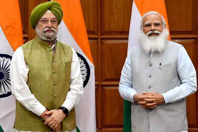 Hardeep Singh Puri standing beside Prime Minister Narendra Modi in front of national flags