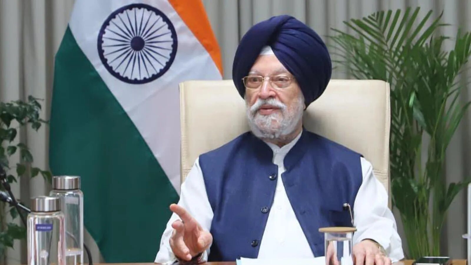 Hardeep Singh Puri speaking from a desk with the national flag behind him during a virtual address